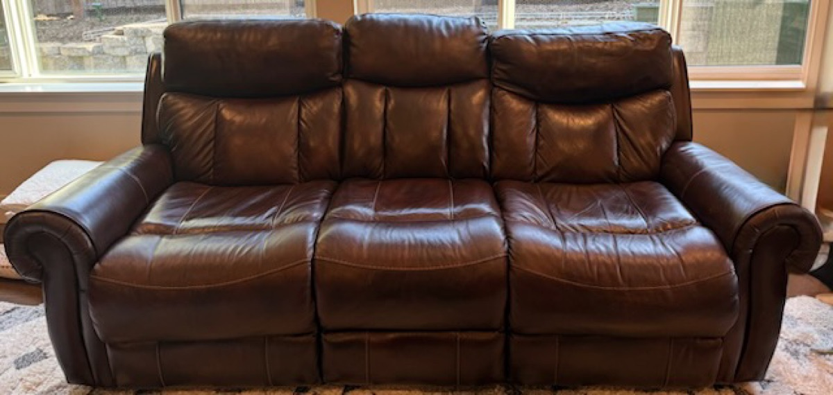 A leather sofa staged for pickup by 99 Junk Removal