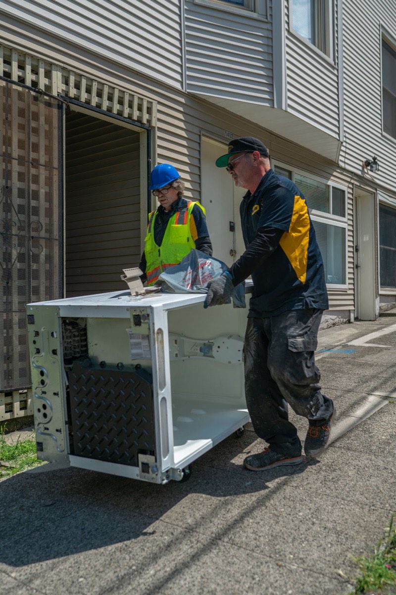 99 Junk Removal crew carrying an appliance out so a Seattle customer skips the transfer station
