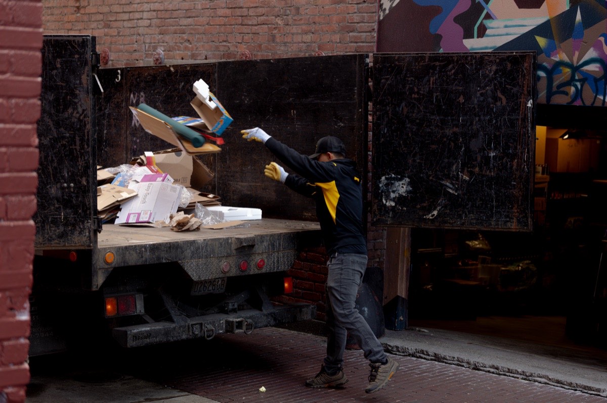 99 Junk Removal crew loading flattened cardboard and junk into the truck on a South Sound job