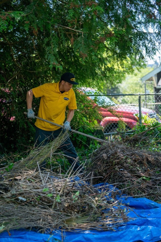 99 Junk Removal crew clearing yard waste and raking debris