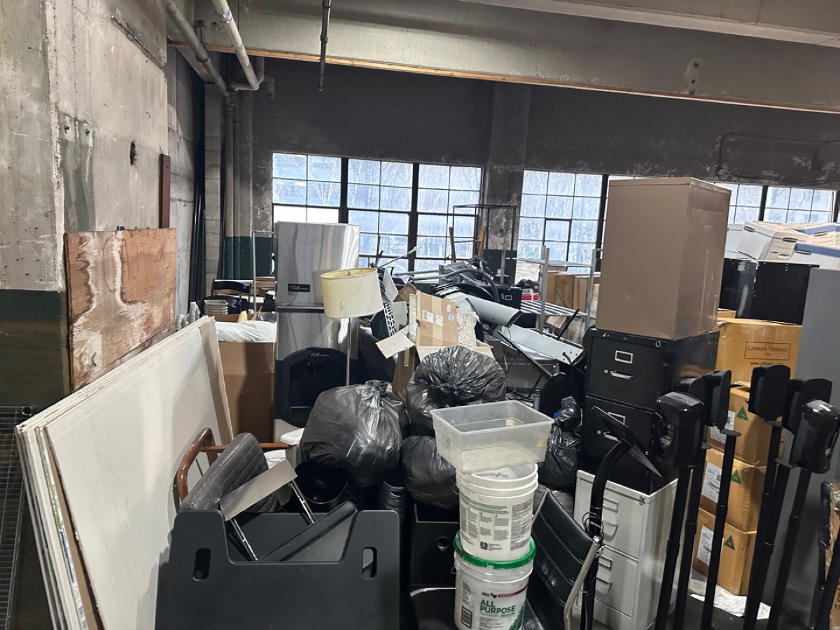Industrial warehouse space packed with inventory, shelving, and equipment before a 99 Junk Removal cleanout
